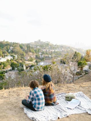 Children enjoying a scenic outdoor picnic on a hilltop with a city view, fostering friendship and adventure.