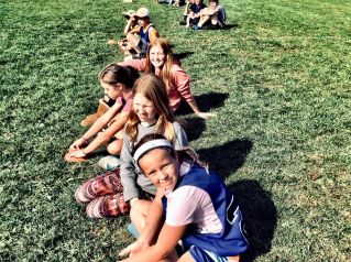 Group of children sitting in a grassy park, enjoying a sunny summer day together.